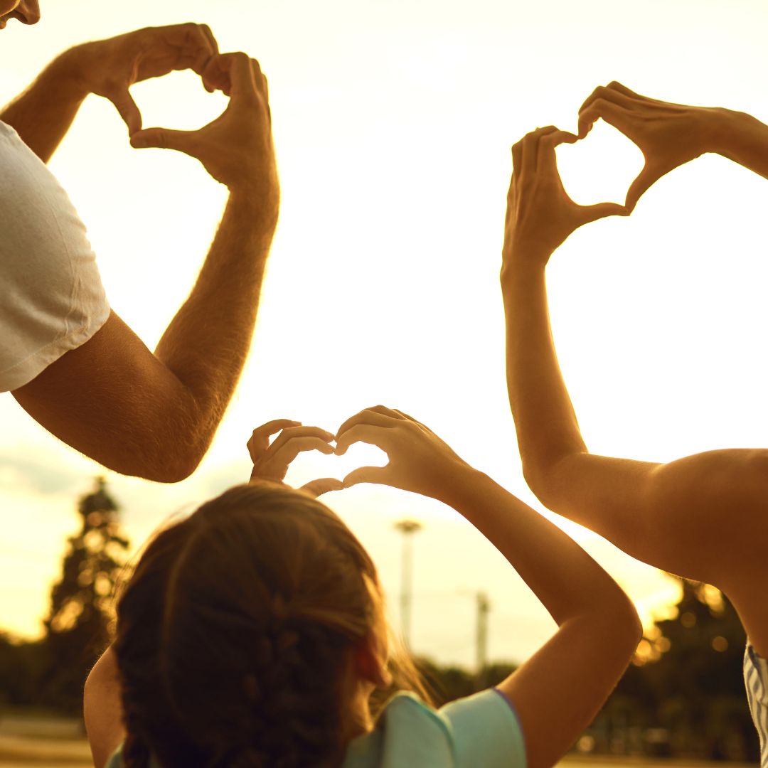 picture of a happy family concept. hands of family group in the shape of heart against the sunset