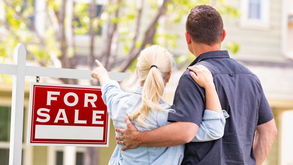 couple pointing to for sale home