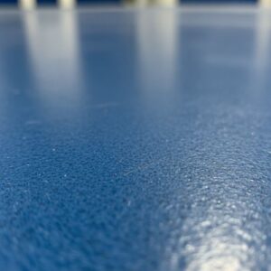 Close-up view of a durable, textured blue polyurea floor coating surface.