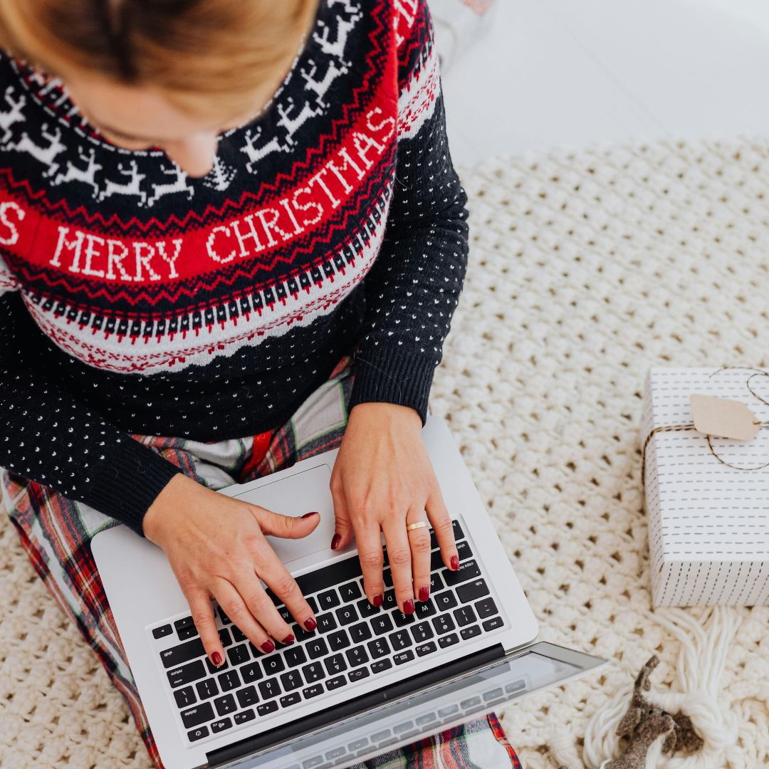 aerial view of woman using laptop, wearing christmas sweater